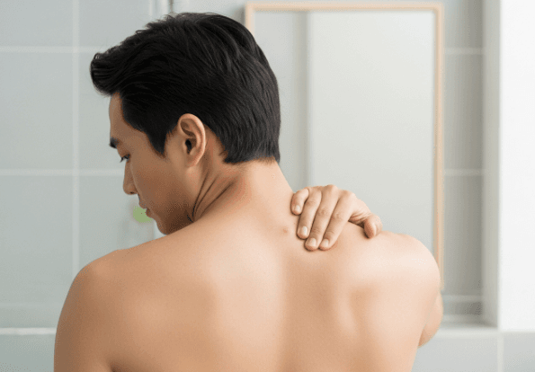 An Asian man examining a small lump on his back, representing a sebaceous cyst or skin concern.